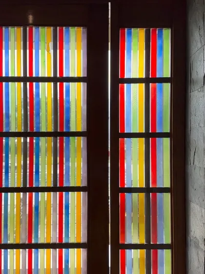 A unique door design featuring vibrant, multi-colored glass panels. This piece turns a simple doorway into a work of art, casting colorful light into the space.