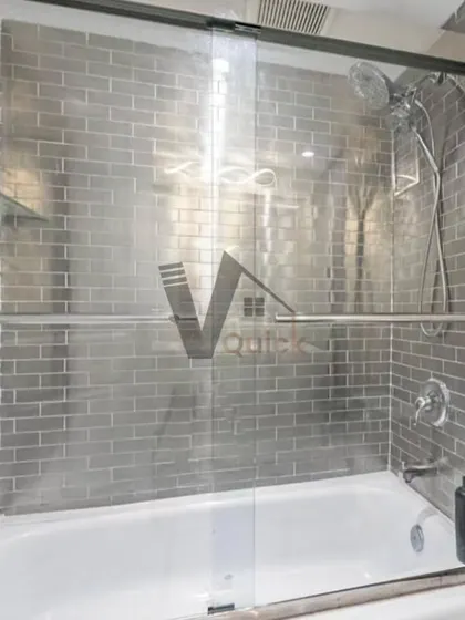 This bathroom design uses grey subway tiles to create a modern, industrial-chic look. A sliding glass door maximizes space in this tub and shower combination, offering a practical and stylish solution for a contemporary home.