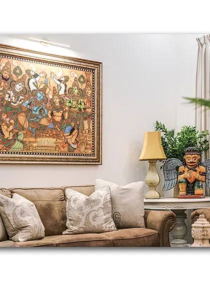 This living room corner is rich with character, featuring a large, intricate traditional painting above a comfortable leather sofa. The quirky winged figurine on the side table adds a playful and unexpected element to the decor.