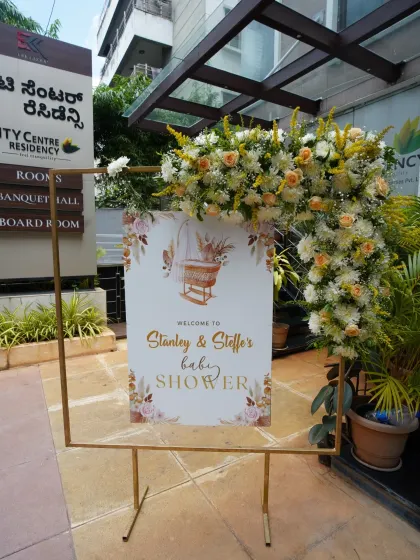 A modern welcome sign for Stanley and Steffe's baby shower, framed with a gold stand and a beautiful fresh flower arrangement.