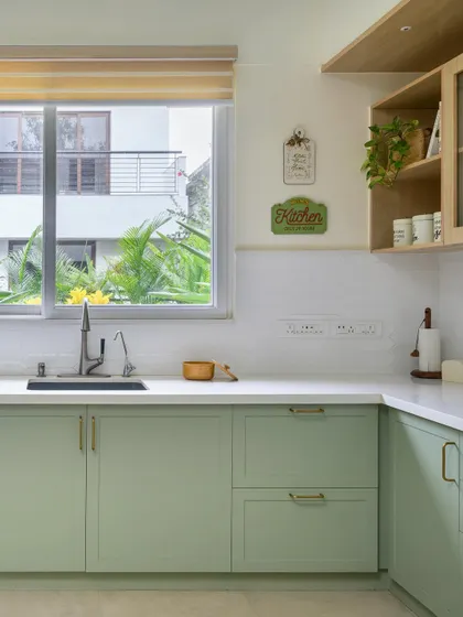 A charming kitchen with sage green shaker-style cabinets and a large window that fills the space with natural light.