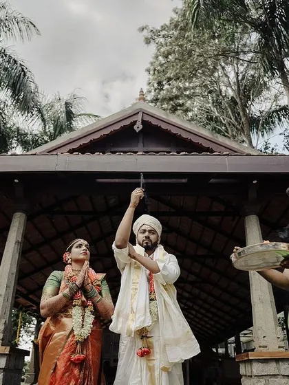 The groom rings a bell, participating in a traditional ritual at the temple like structure. This shot captures a moment of spiritual observance amidst the wedding celebrations.