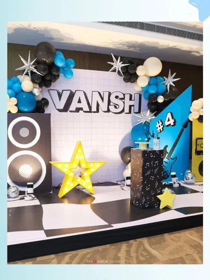 A full view of the dynamic stage we created for Vansh's 4th birthday. The setup includes speakers, a light-up star, a guitar graphic, and a checkerboard floor to complete the rockstar look.