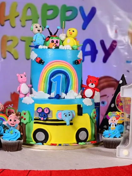 The centerpiece of a Cocomelon party: a two-tier themed cake surrounded by matching cupcakes. I can arrange for custom cakes and desserts to perfectly match your theme.