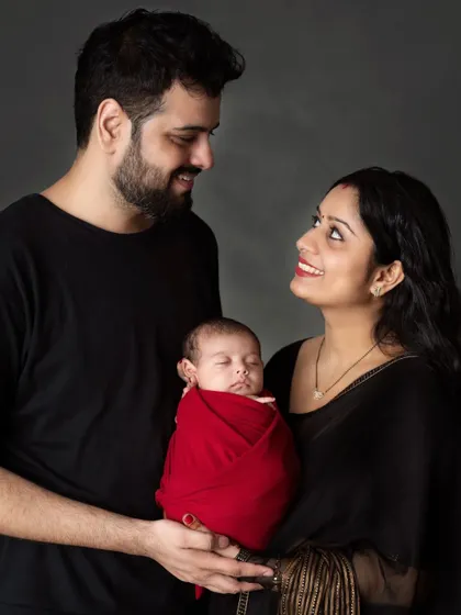 A loving gaze between new parents as they present their sleeping baby to the world.