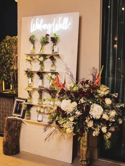 A custom "Wishing Well" for an anniversary party, where guests can leave notes for the couple. The neon sign and individual flower-filled vases make it a charming and interactive decor element.