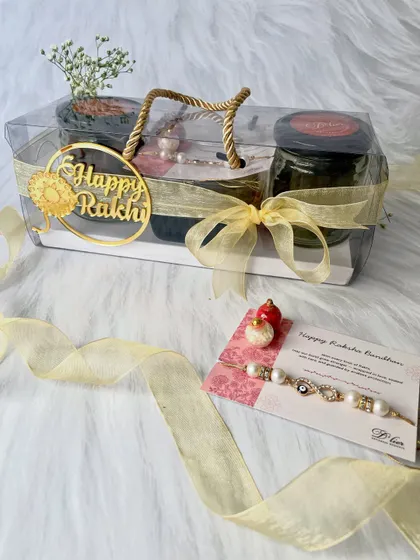 This is our thoughtfully curated Rakhi Indulgence Hamper. It comes in a clear, easy-to-carry box and includes jars of coffee chocolate cookies and mini brownies, a beautiful Rakhi, a heartfelt note, and traditional kumkum chawal for the ceremony.