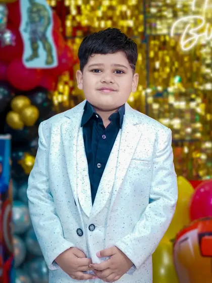 A young boy looking sharp in a white suit at his superhero-themed birthday party. We take individual portraits of the kids, making them feel like the star of the show.
