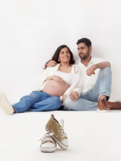 Using selective focus to draw attention to the tiny baby shoes in the foreground, this shot tells a story of a couple eagerly awaiting their new arrival. It's a creative and heartfelt announcement photo.