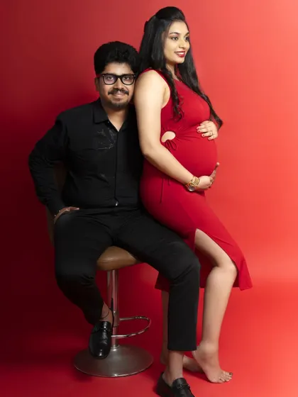 A stylish and confident pose for the parents-to-be. The vibrant red background makes this a striking and memorable maternity portrait.