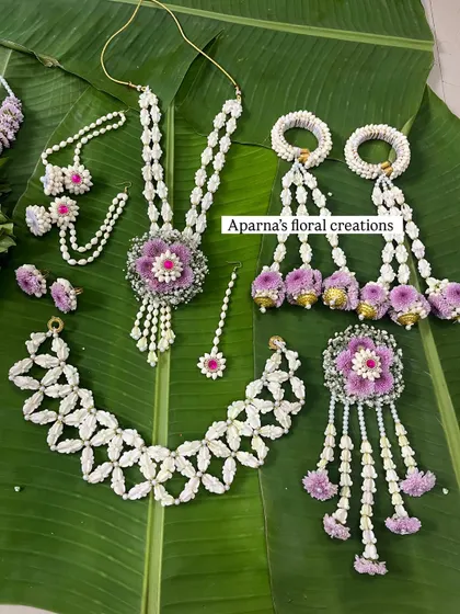 A full baby shower jewellery set featuring purple and white flowers. This set includes a choker, long necklace, bajuband with kaleere, maang tikka, and a brooch.