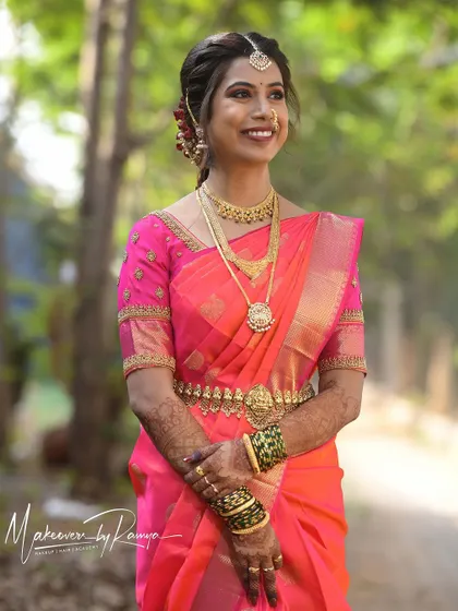 Santhoshi looking absolutely radiant on her wedding day. Her bright pink Kanjeevaram saree is perfectly complemented by a fresh, dewy makeup look and a classic bridal hairstyle.