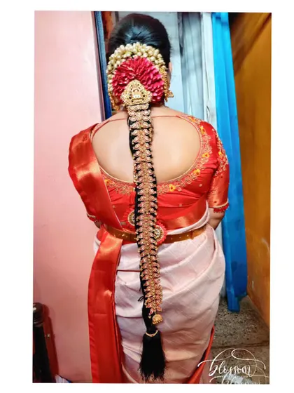 Another gorgeous muhurtham jade hairstyle. The combination of the red flowers and the gold jewellery creates a vibrant and classic look, perfect for a traditional wedding ceremony.