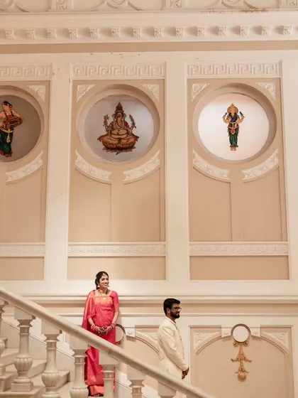A grand portrait of a couple on the staircase of the Lalitha Mahal Palace, a venue that offers a truly royal wedding experience.