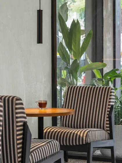 We love this soft, subtle palette of striped upholstery and warm wood against a concrete-finish wall. It holds its own character while celebrating Bangalore’s beautifully green outdoors, visible through the large window.