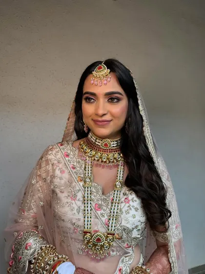 Elegant, soft waves for a bride in a beautiful pastel lehenga. This open hairstyle is perfect for a daytime wedding, creating a romantic and ethereal look.