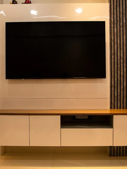 The full view of the TV unit, showcasing the balance between the glossy white console, the textured wood paneling, and the artistic feather detail.