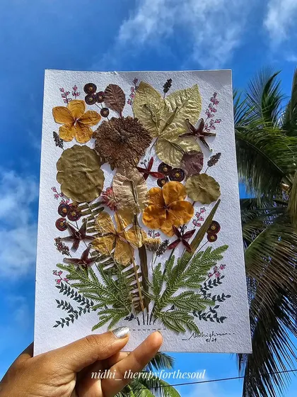 Another shot of the pressed flower art held against the sky, a perfect representation of nature-inspired art.