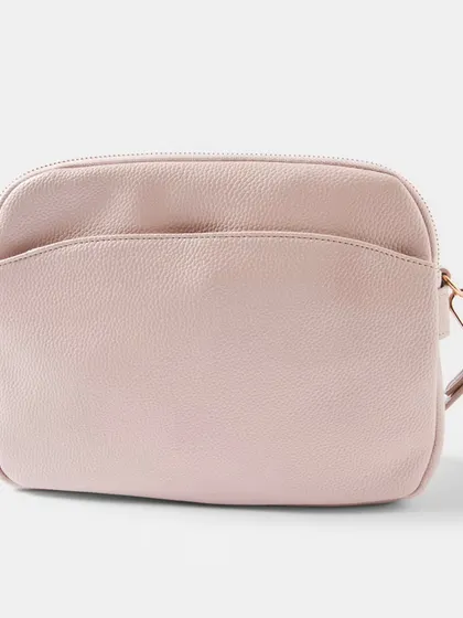 The Australia Crossbody bag in a soft, dusty pink colour. The rose gold hardware adds a warm, feminine touch to the design.