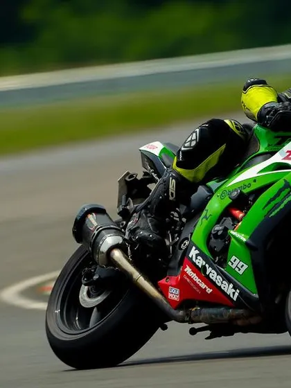 A rider on a green Kawasaki ZX-10R demonstrates perfect cornering technique at Madras International Circuit, a testament to the skills honed at our sessions.