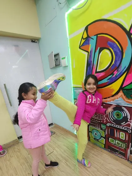 It's all about progress, not perfection. This student is getting closer to her split with the help of a friend, showing great determination.