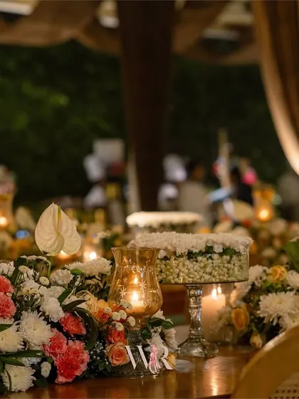 Another detail of the rustic dining table, showing the mix of white and pink florals with pillar candles. The warm lighting from the candles and chandeliers enhances the cozy feel.