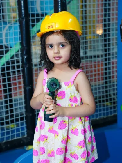 Ready for some construction fun! A toddler wears a hard hat and holds a toy drill in our role-playing area.
