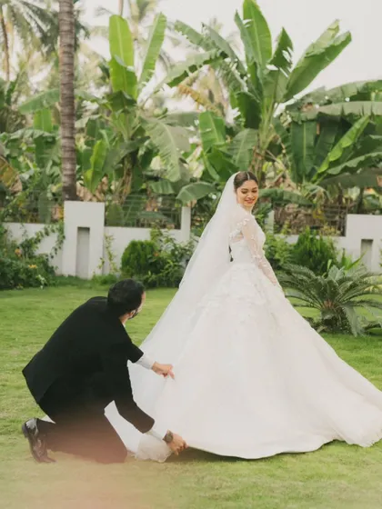 A playful moment between the bride and groom. The groom adjusting the bride's magnificent gown shows their connection and care for each other.