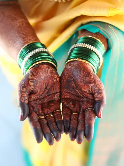 The rich, dark mehendi stain looks stunning paired with these traditional green glass bangles, perfect for any festive occasion.