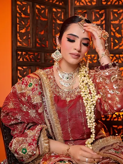 A candid-style portrait of the model adjusting her jewelry. This shot provides a sense of intimacy and highlights the beautiful hand jewelry and embroidered velvet fabric.
