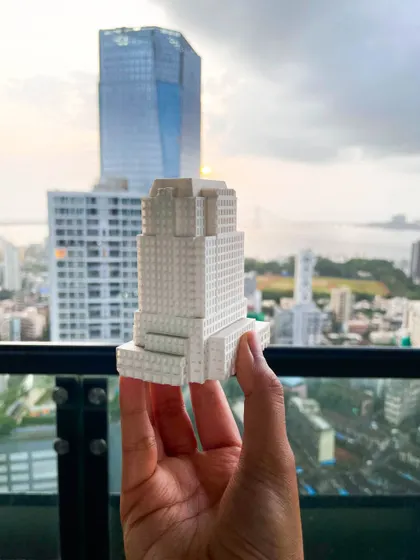 A conceptual 3D-printed model held against the Mumbai skyline, showing an early-stage design for a high-rise building. These physical models allow us to study the building's form and scale in a real-world context.