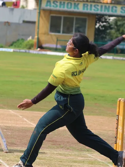 A side-on view of a bowler's action, with our pavilion visible in the background.
