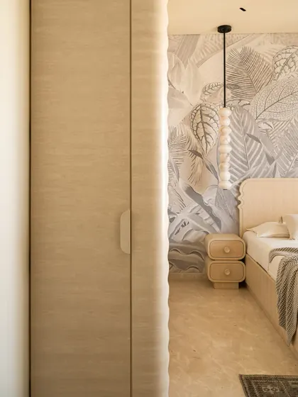 A peek into the guest bedroom, highlighting the rippled edge of the wardrobe door and the soft, organic forms of the furniture.