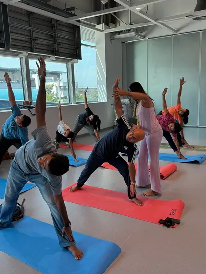 Assisting a participant in Triangle Pose (Trikonasana) to help him find better alignment. Hands-on adjustments ensure a safer and more effective practice.