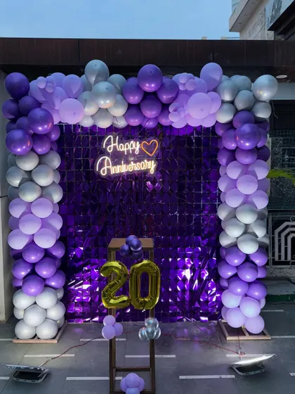 A full view of the outdoor anniversary setup, showing the impressive scale of the balloon arch and shimmer wall.