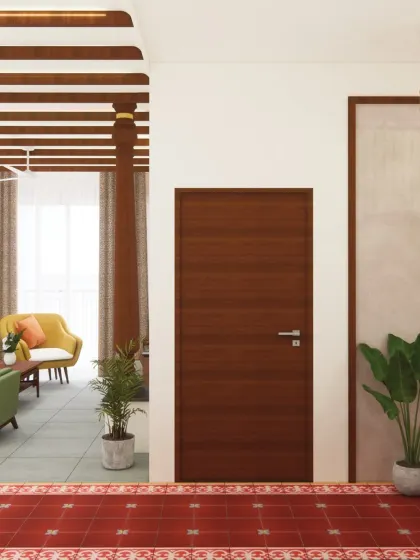 A clean, simple wooden door stands in contrast to the textured red Athangudi tile floor, creating a moment of minimalist calm. The design balances intricate traditional details with modern simplicity.