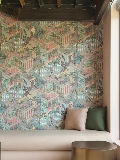 A cozy nook is transformed by the 'Miami' wallpaper from Cole & Son. The intricate, multi-layered design adds depth and character, proving that even a small wall can make a significant stylistic impact.