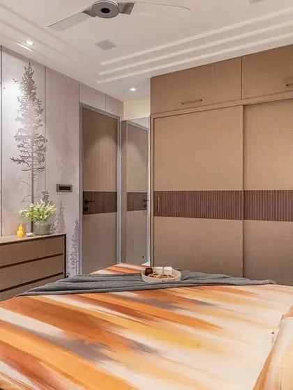 This shot displays the custom sliding wardrobe with textured fabric-like laminate panels. The design complements the earthy palette and the nature-inspired wallpaper, creating a cohesive and harmonious space.