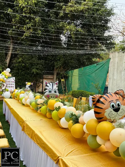 A closer look at the playful table runner for the kids' seating area. Large foil balloons shaped like a tiger and zebra pop out from the arrangement, adding a delightful touch to the safari birthday party decor.