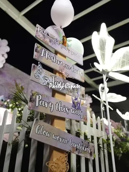 Custom signage for a butterfly-themed party, with glowing butterfly lights. The signs guide guests to different areas like the photo booth and main stage, all while staying on theme.