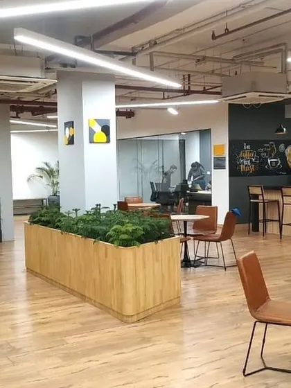 The central hub of the VentureX office, showing the integration of the pantry, breakout tables, and a branded feature wall. This space is designed to be the social core of the office.