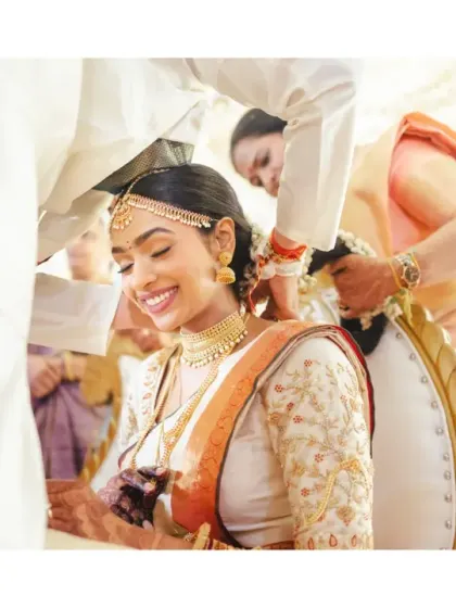 A tender moment as the bride's jewellery is adjusted during the ceremony. Her gentle smile and the soft, bright lighting create a beautiful and serene image.