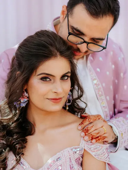 A tender moment between Sahas and Rozy during their carnival-themed event. The groom's gentle touch and the bride's confident gaze create a beautiful dynamic.