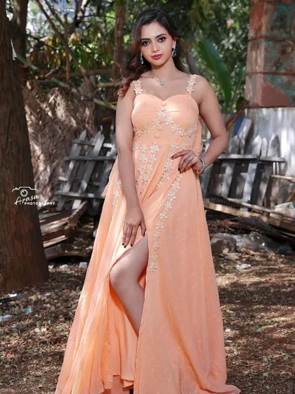 I designed this peach-colored gown with a thigh-high slit and delicate floral appliqué work. It's a romantic and modern design, perfect for a photoshoot or a special event.