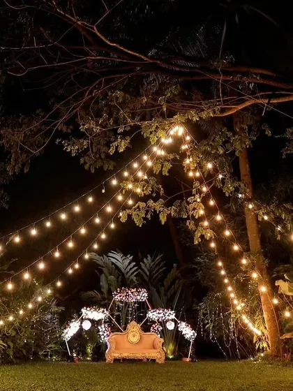 An intimate outdoor seating area set under a canopy of string lights. This setup creates a cozy and romantic atmosphere, perfect for a sangeet or reception under the stars.
