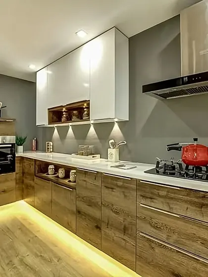This modern kitchen features rustic wood-finish cabinets with sleek, handleless doors. The under-cabinet and toe-kick lighting adds a warm, ambient glow and makes the space feel more inviting.