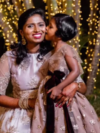A sweet kiss from daughter to mother, both looking elegant in their coordinated party gowns.