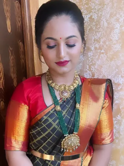 An elegant look with a black and red saree, paired with a stunning green beaded necklace. The makeup is kept classic to let the jewellery stand out.