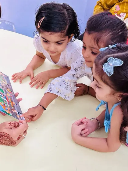 Three girls are completely captivated by a picture book their trainer is showing them. This moment highlights the power of storytelling to spark curiosity and imagination.