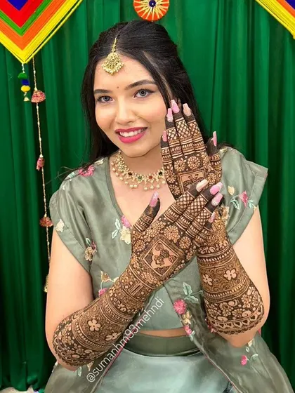 This bride is glowing. Her full arm mehndi features a personalized portrait, surrounded by classic floral and geometric patterns, creating a design that is both traditional and deeply personal.